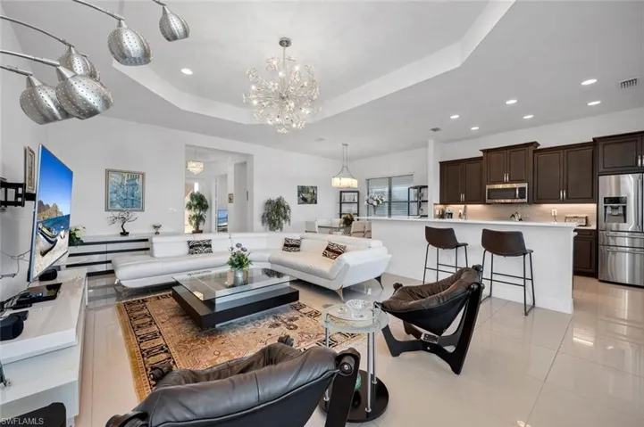 Living room featuring an inviting chandelier, light tile patterned floors, and a tray ceiling