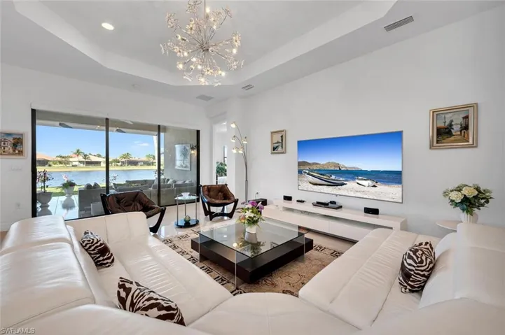 Living room featuring a raised ceiling, a water view, and a notable chandelier