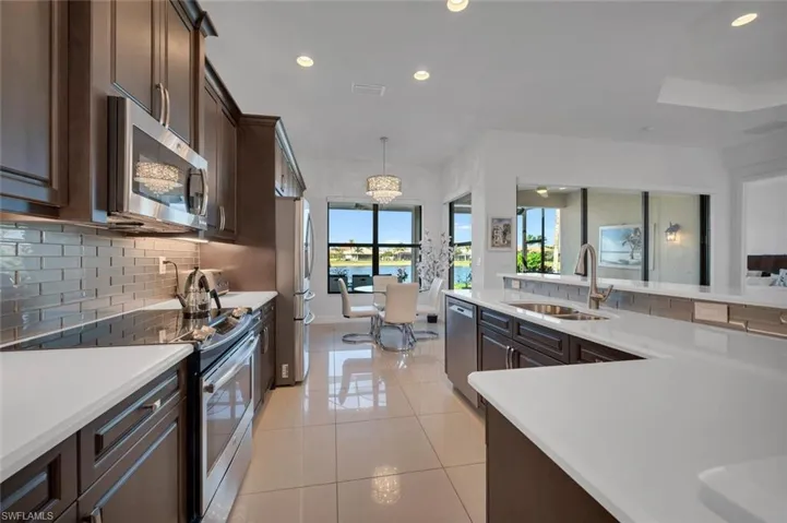 Kitchen featuring pendant lighting, an inviting chandelier, sink, light tile patterned floors, and stainless steel appliances