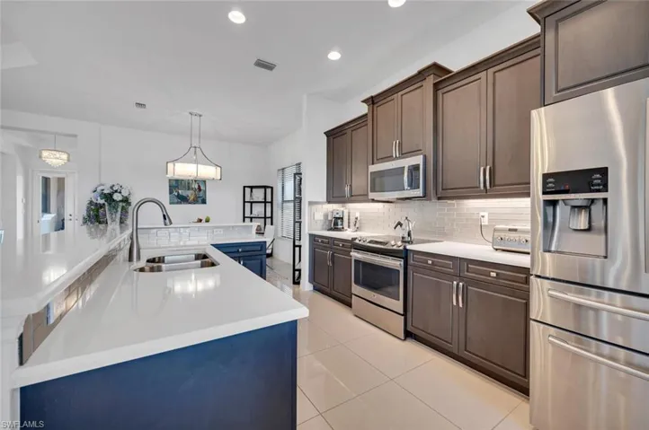 Kitchen with sink, hanging light fixtures, light tile patterned floors, dark brown cabinets, and stainless steel appliances