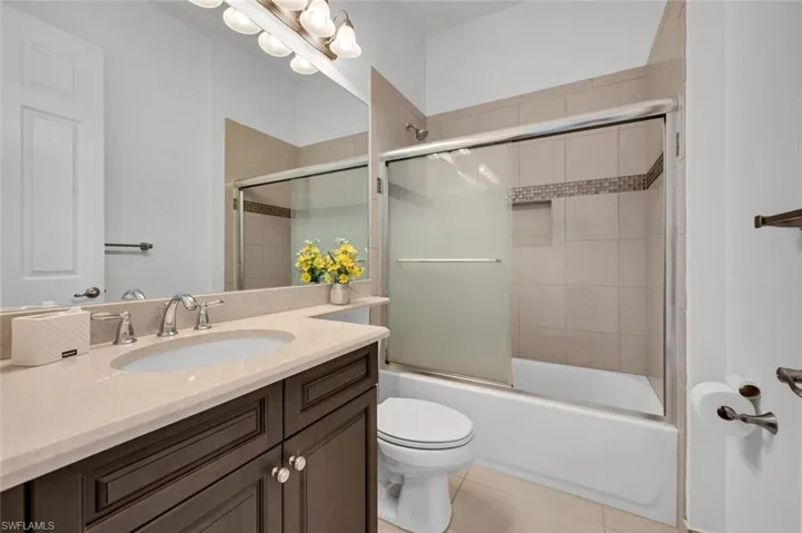 Full bathroom with tile patterned floors, vanity, toilet, and shower / bath combination with glass door