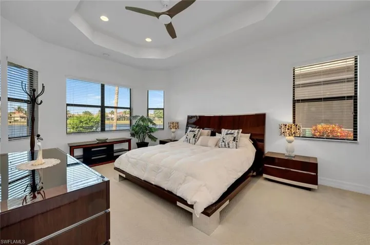 Bedroom featuring carpet flooring, ceiling fan, and a tray ceiling
