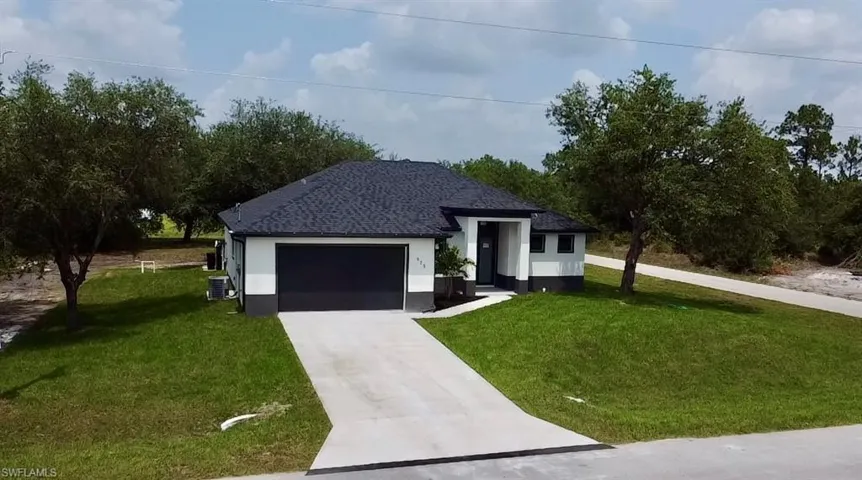 View of front of home featuring central AC, a front lawn, and a garage