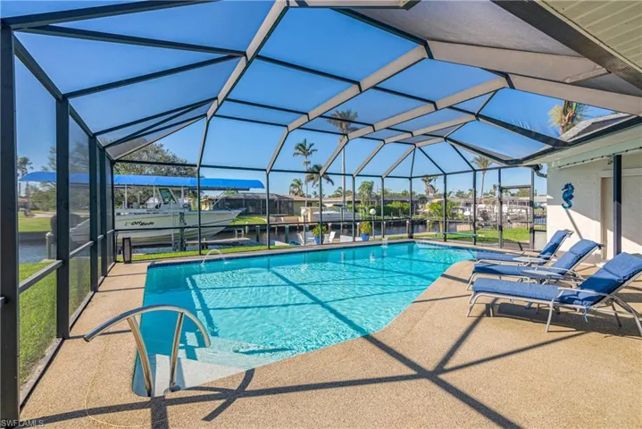 View of pool with glass enclosure, a patio area, and a water view