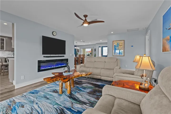 Living room with ceiling fan and dark wood-type flooring