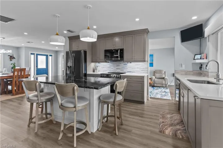 Kitchen with pendant lighting, light hardwood / wood-style floors, sink, and stainless steel appliances