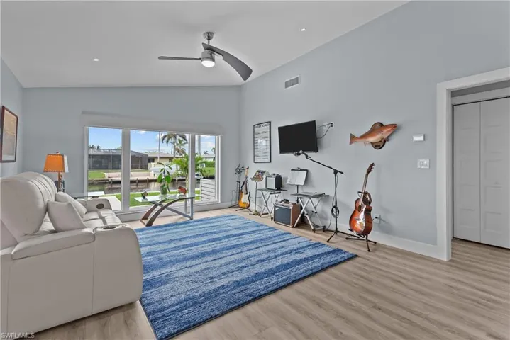 Living room featuring light wood-type flooring, high vaulted ceiling, and ceiling fan