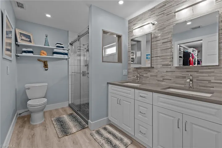 Bathroom with decorative backsplash, vanity, a shower with door, hardwood / wood-style flooring, and toilet