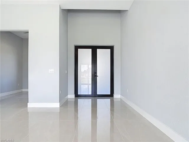 Unfurnished room featuring french doors and baseboards