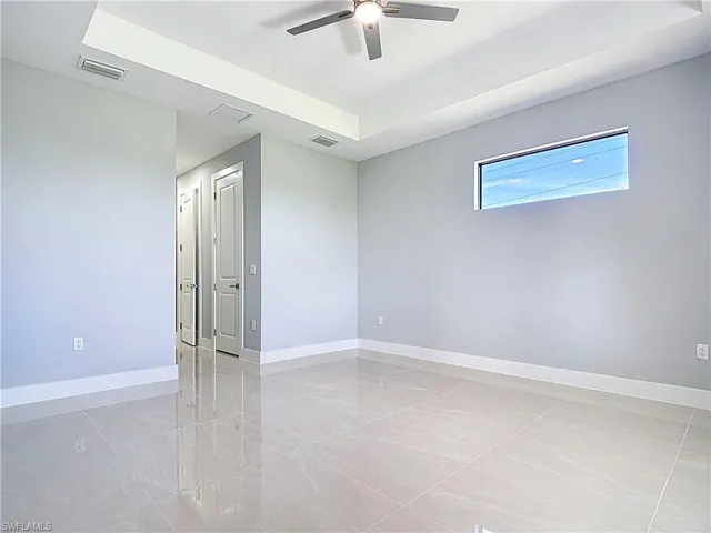 Empty room featuring a raised ceiling and ceiling fan