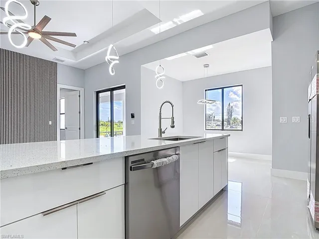 Kitchen featuring modern cabinets, white cabinetry, plenty of natural light, and stainless steel dishwasher