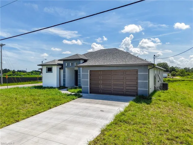 View of front facade with a front yard, stucco siding, and concrete driveway
