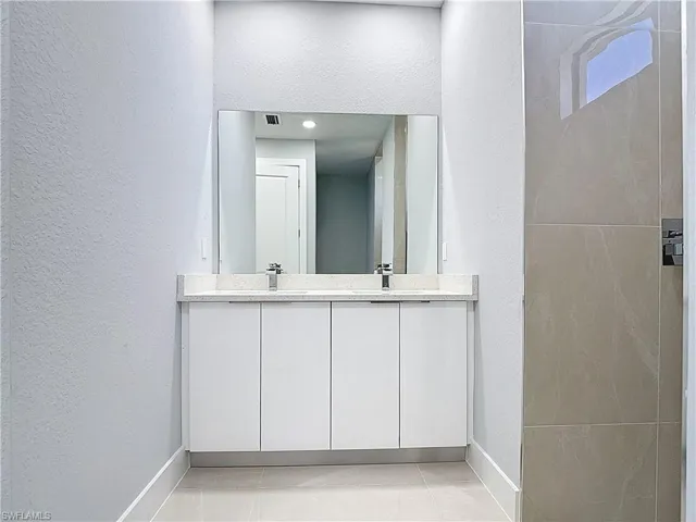 Full bathroom featuring a textured wall and double vanity