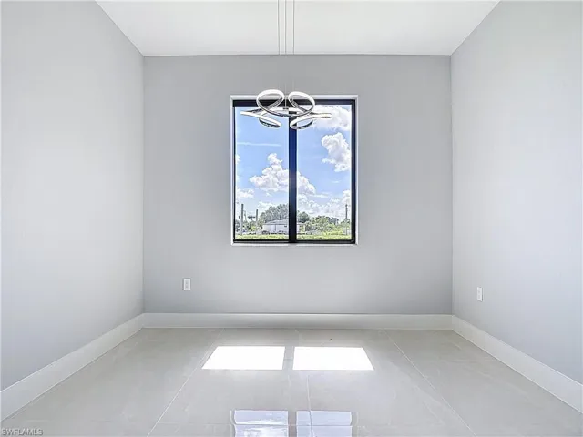Empty room featuring baseboards and hanging lights