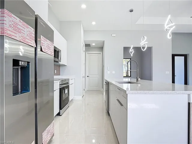 Kitchen with stainless steel appliances, a kitchen island with sink, modern cabinets, and pendant lighting