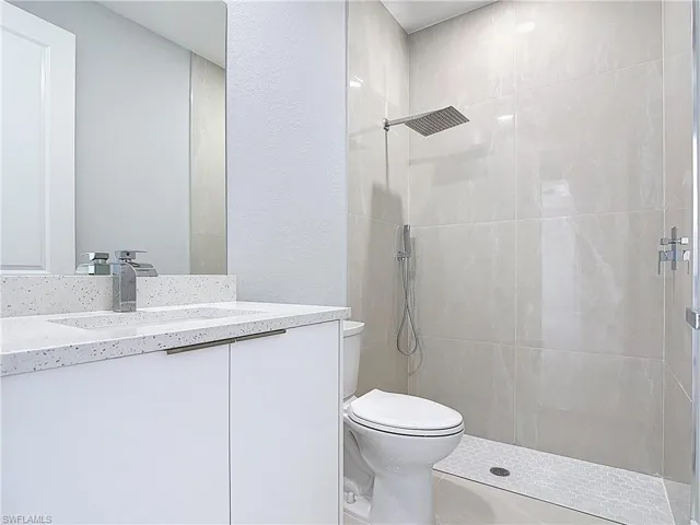 Full bathroom with vanity, a textured wall, and a tile shower