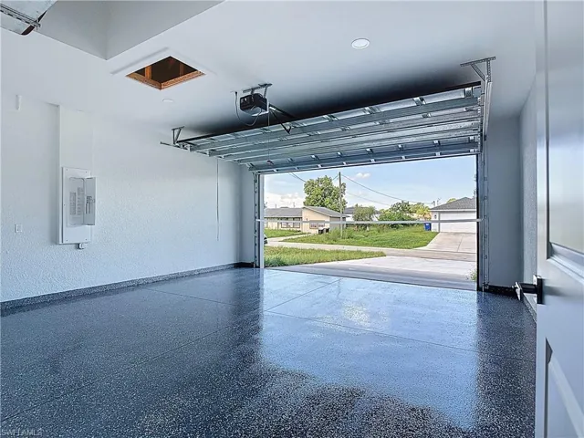 Garage with a textured wall, electric panel, a residential view, and a garage door opener