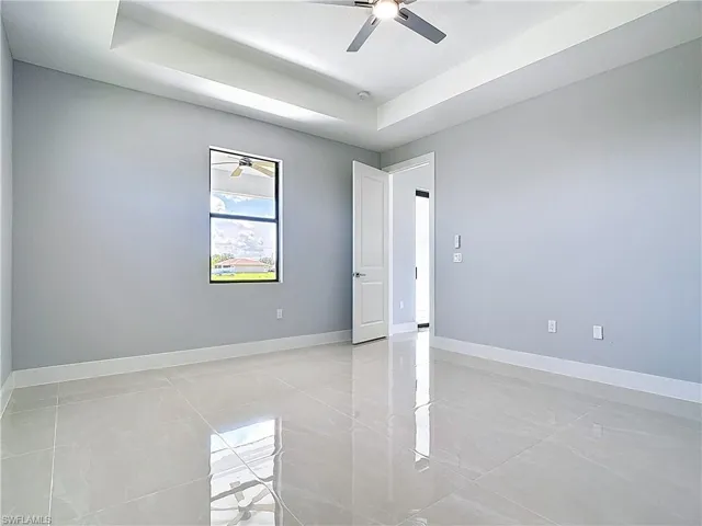 Empty room with a raised ceiling and a ceiling fan