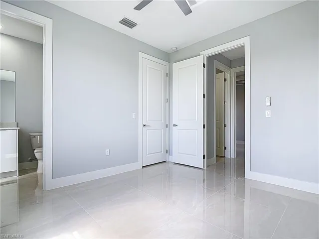 Unfurnished bedroom featuring ensuite bath and a ceiling fan