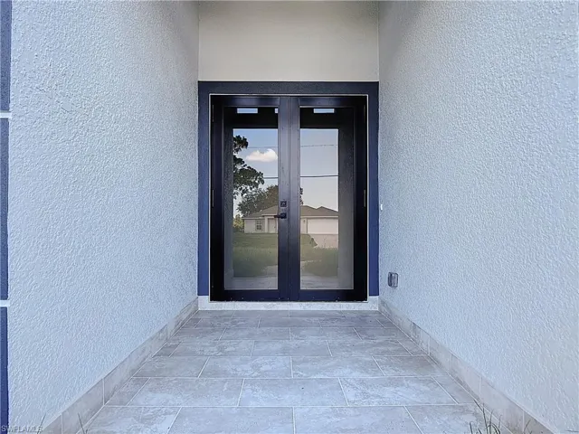 View of exterior entry featuring french doors and stucco siding