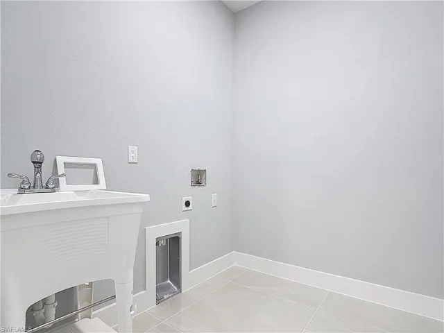 Laundry area featuring washer hookup, hookup for an electric dryer, a textured wall, and light tile patterned floors
