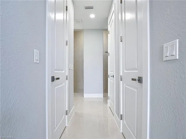 Corridor with a textured wall and recessed lighting
