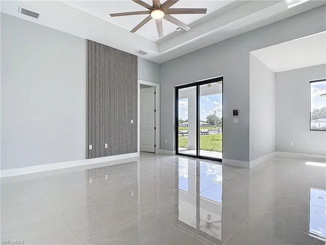 Empty room featuring a ceiling fan and a tray ceiling