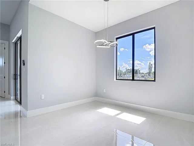 Spare room with baseboards and suspended lighting