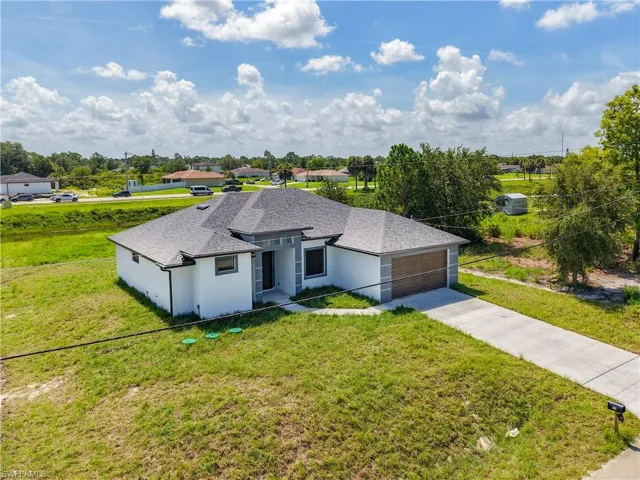 Ranch-style home featuring a front lawn, stucco siding, a shingled roof, a garage, and driveway