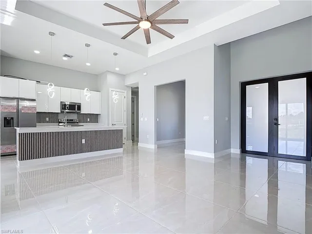 Kitchen featuring white cabinets, stainless steel appliances, modern cabinets, a kitchen island with sink, and decorative light fixtures