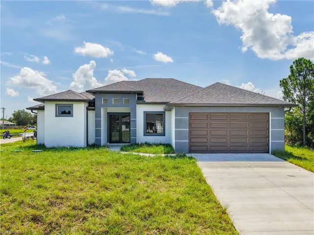 Prairie-style house featuring stucco siding, concrete driveway, an attached garage, a front lawn, and a shingled roof