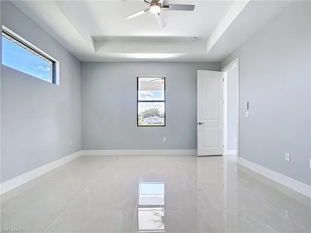 Spare room featuring a tray ceiling, healthy amount of natural light, and ceiling fan
