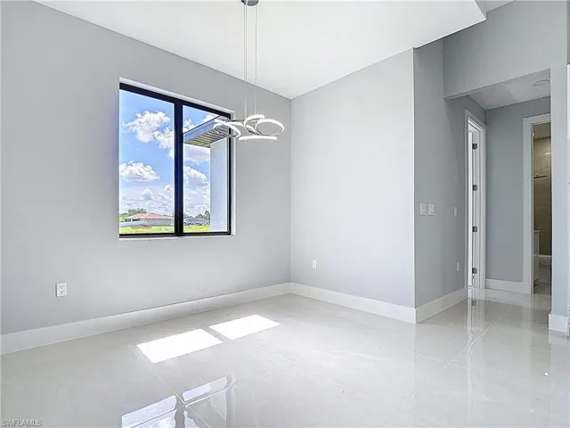 Unfurnished dining area featuring baseboards and a chandelier