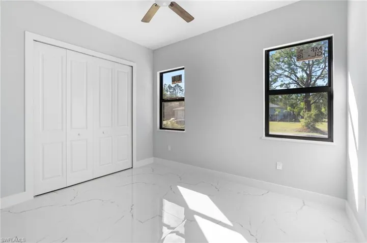 Unfurnished bedroom featuring light marble finish floors, a closet, and ceiling fan