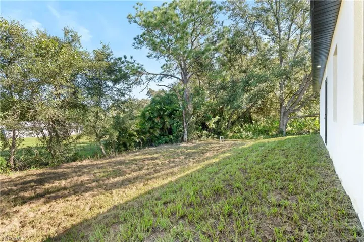 View of grassy yard with view of wooded area