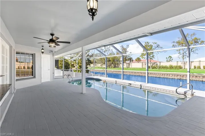 View of pool with glass enclosure and a water view