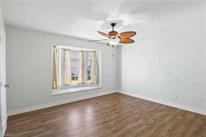 Empty room with ceiling fan and dark hardwood / wood-style flooring