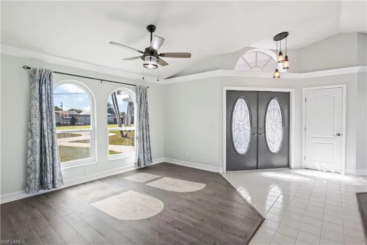 Foyer with ceiling fan, french doors, crown molding, vaulted ceiling, and hardwood / wood-style flooring
