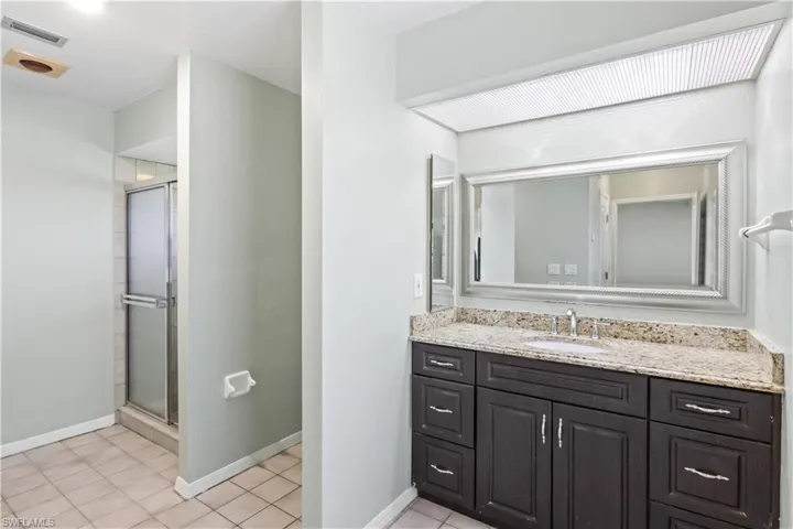 Bathroom featuring tile patterned floors, vanity, and walk in shower
