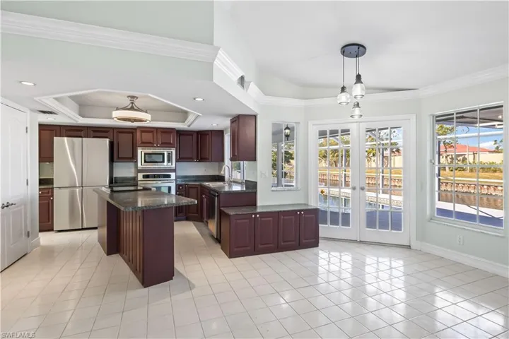 Kitchen with french doors, hanging light fixtures, sink, appliances with stainless steel finishes, and a kitchen island