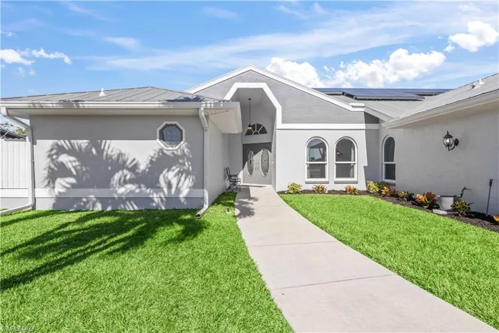 View of front of property with a front lawn and solar panels