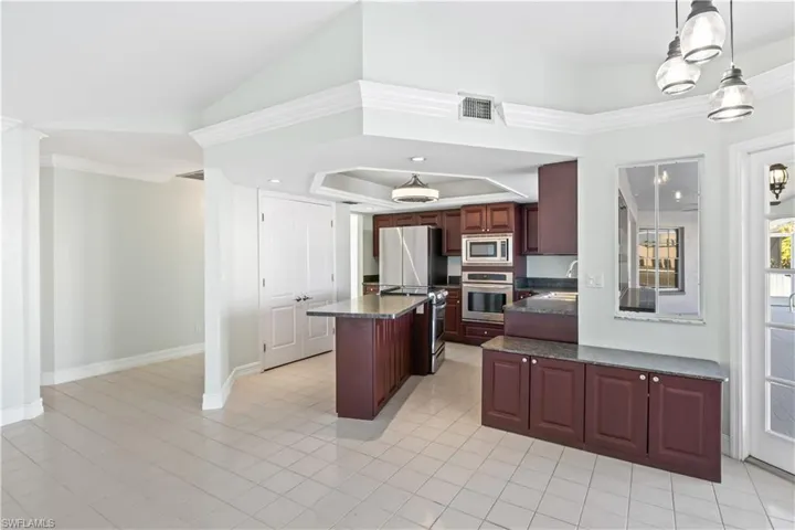 Kitchen featuring a center island, crown molding, decorative light fixtures, light tile patterned flooring, and appliances with stainless steel finishes