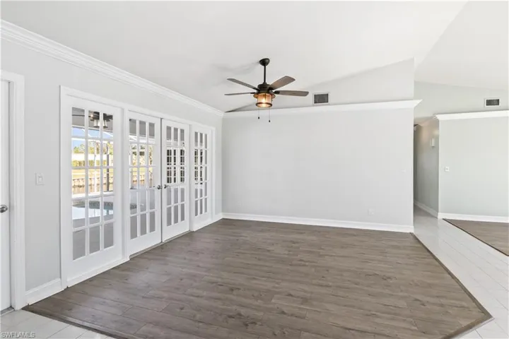 Empty room featuring french doors, ceiling fan, lofted ceiling, and wood-type flooring