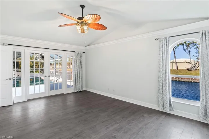 Unfurnished room with dark hardwood / wood-style floors, french doors, a healthy amount of sunlight, and vaulted ceiling