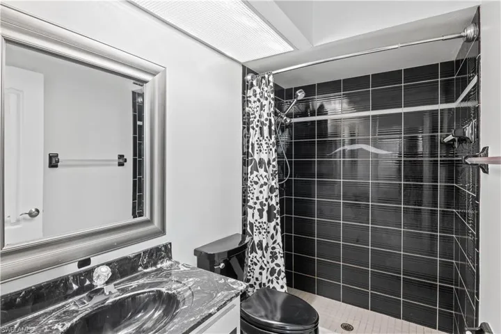 Bathroom with a shower with curtain, vanity, and toilet