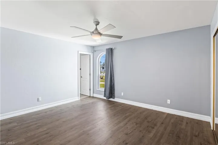 Empty room featuring ceiling fan and dark hardwood / wood-style flooring