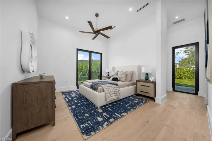 Bedroom featuring visible vents, high vaulted ceiling, light wood-style flooring, and access to exterior