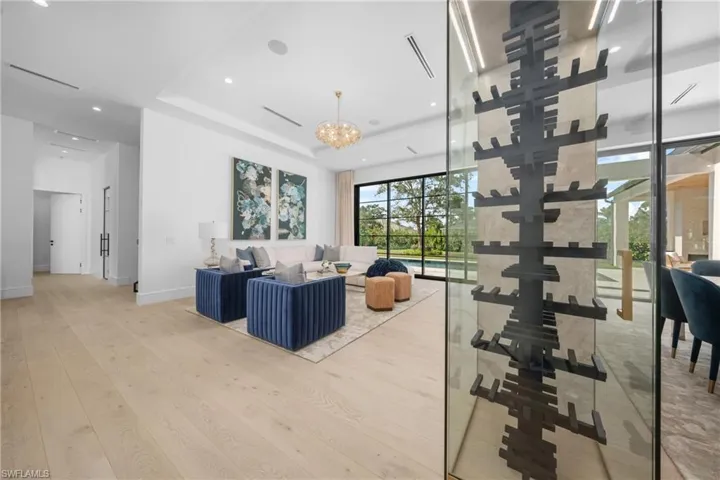 Living area featuring a tray ceiling, a notable chandelier, recessed lighting, wood finished floors, and baseboards