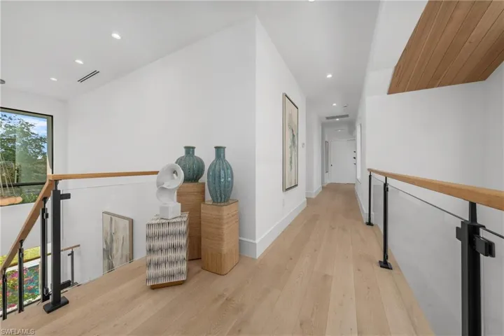 Hall featuring recessed lighting, light wood-style flooring, visible vents, and an upstairs landing