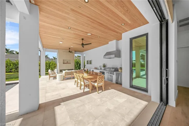 View of patio with ceiling fan, an outdoor living space with a fireplace, a grill, exterior kitchen, and outdoor dining space